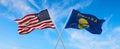 two flags of USA and state of Montana waving in the wind on flagpoles against sky with clouds on sunny day