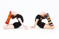 Two flexible teen girls doing gymnastics exercises on a white