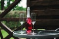 Two flute glasses and an pink champagne bottle with no label on a glass table in a back yard. Royalty Free Stock Photo