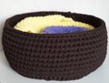 Two folded knitted blankets in the brown basket on the white table