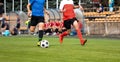 Two football players in running duel. Soccer teenage boys running fast with the ball. Players sitting on a substitute bench Royalty Free Stock Photo