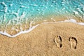 Two footprints on yellow sand, blue sea wave, white foam top view close up, turquoise ocean water, summer vacations concept Royalty Free Stock Photo