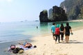 Two foreigners sunbathing and Thai tourist goup walk