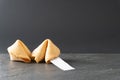 Two fortune cookies rest on a black slate table top with a blank fortune and copy space Royalty Free Stock Photo