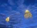 two frayed straw outdoor lamps lit at blue hour with a sky with clouds in a chill out atmosphere, summer nights at the beach at Royalty Free Stock Photo