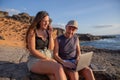 Two freelancers work at the beach, girl makes a phone call, boy uses laptop Royalty Free Stock Photo