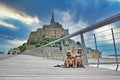 Two French Bulldog dogs sightseeing on vacation on bridge in front of famous French landmark `Le Mont-Saint-Michel`