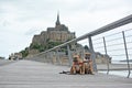 2 French Bulldog dogs sightseeing on vacation on bridge in front of famous French landmark `Le Mont-Saint-Michel` in background