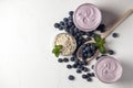 Two fresh blueberry yogurt with blueberries and cereals on a white texture table, ingredients for cooking Royalty Free Stock Photo