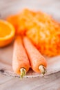 Two fresh carrots and a pile of grated carrot and half an orange