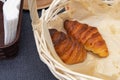 Two fresh croissants in a wicker basket. French croissants