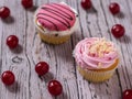 Two fresh cupcakes and scattered cherries on a wooden table. Royalty Free Stock Photo