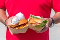 Two fresh delicious grilled burgers in man`s hands. Street food festival