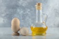 Two fresh eggs in eggcup and on ground with bottle of oil on white background Royalty Free Stock Photo