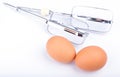Two fresh eggs with set of auto beater whisks on white backgroun Royalty Free Stock Photo