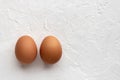 Two fresh eggs on white textural background with egg`s shadow Royalty Free Stock Photo