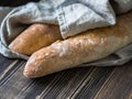 Two fresh French homemade baguettes under a linen towel