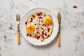 Two fresh fried eggs with crunchy crisp bacon and chive served on rustic plate Royalty Free Stock Photo