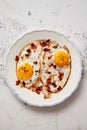 Two fresh fried eggs with crunchy crisp bacon and chive served on rustic plate Royalty Free Stock Photo