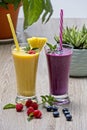 Two fresh fruit smoothies with berries lying in front of glasses