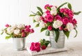 two fresh garden bouquets of roses in decorative buckets stand on a white wooden podium. grey concrete table. white Royalty Free Stock Photo