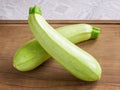 Two fresh green courgettes or zucchini criss-cross on a brown wooden cutting board. Cook at home. Fresh vegetables, vegetarianism