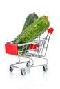 Two fresh green cucumbers in the chromed toy market shopping cart with red handle and plastic board on the front with reflection