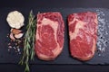 Two fresh raw marble meat, black Angus ribeye steak with spices on a dark stone background Royalty Free Stock Photo