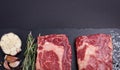 Two fresh raw marble meat, black Angus ribeye steak with spices on a dark stone background. Royalty Free Stock Photo