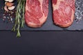 Two fresh raw marble meat, black Angus ribeye steak with spices on a dark stone background. Royalty Free Stock Photo