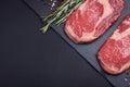 Two fresh raw marble meat, black Angus ribeye steak with spices on a dark stone background. Royalty Free Stock Photo