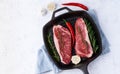 Two fresh raw pieces of meat, beef fillet, marble striploin in cast-iron large pan. Top view