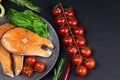 Two fresh raw salmon steaks with vegetables and spices: rosemary, tomatoes, peppers, basil, lemon and olive oil Royalty Free Stock Photo