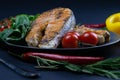 Two fresh raw salmon steaks with vegetables and spices: rosemary, tomatoes, peppers, basil, lemon and olive oil Royalty Free Stock Photo