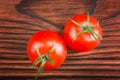 Two fresh ripe and juicy tomatoes from a greenhouse on the dark brown wooden table. Healthy and useful red tomatoes with leaves. Royalty Free Stock Photo