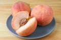 Two Fresh Ripe Peach Whole Fruits and One Cut Peach on a Blue Plate Served on Wooden Table Royalty Free Stock Photo