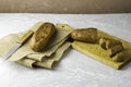 two fresh rye buns on a cutting wooden board and a piece of burlap one of the buns is cut there is a knife next to it