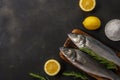 Two fresh seabass fishes with rosemary and lemon on black table. Seafood concept