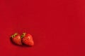 Two fresh strawberries on red textile background