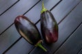 Two fresh, uncooked eggplants are arranged on a black wooden background
