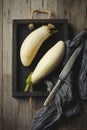 Two fresh white eggplants in a vintage box on an old wooden background Selective focus. Top view. Copy space.Toned imag