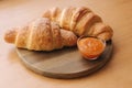 Two freshly baked criossant on wooden table at home. Vegan empty croissant. Apricot jam on a plate. Homemade croissant