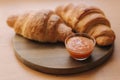 Two freshly baked criossant on wooden table at home. Vegan empty croissant. Apricot jam on a plate. Homemade croissant