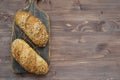 Two freshly baked crunchy bread rolls with a golden crust on wooden cutting board and copy space on wooden background Royalty Free Stock Photo