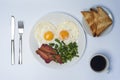 Two fried eggs with green beans and bacon on white plate, knife, fork, toasts and cup of coffee on light background. Royalty Free Stock Photo