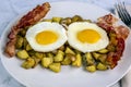 two fried eggs on home fries and bacon Royalty Free Stock Photo