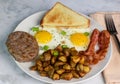 two fried eggs served with bacon sausage and home fries