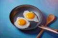 Two fried eggs sizzle in pan, wooden spoon centerpiece