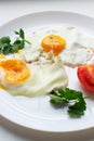 Two fried eggs with tomatoes and herbs on a white plate. Ugly food concept. Vertial orientation.