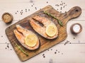 Two fried fresh salmon steak with unground pepper, spices , lemon on a cutting board top view Royalty Free Stock Photo